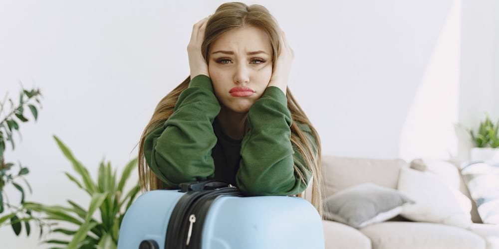 nő kanapén ülve jet lag után bőrönddel